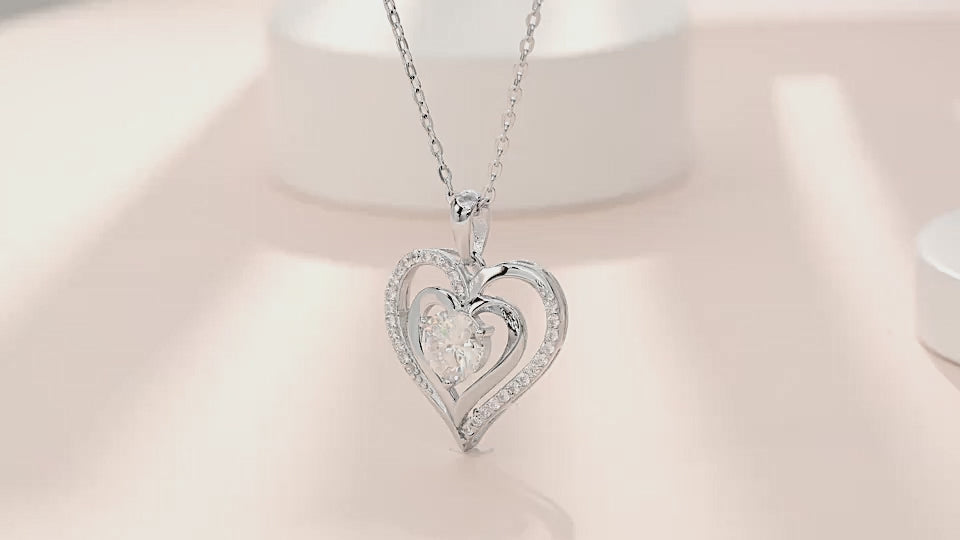 Moissanite heart necklace shown on a pearlescent blush background